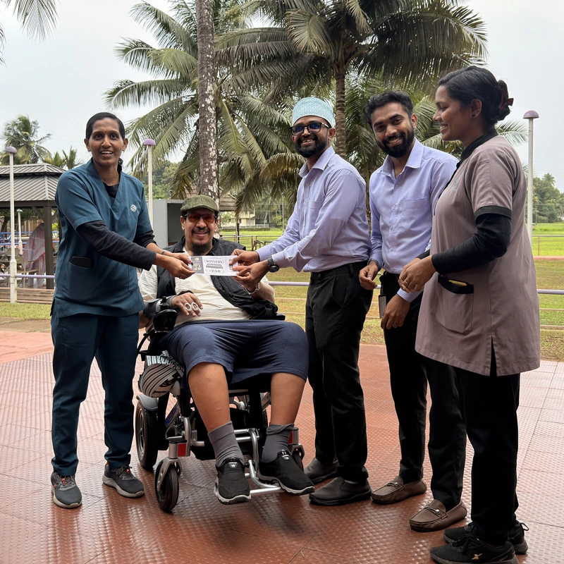 Multidisciplinary rehabilitation team presenting milestone award to patient in wheelchair